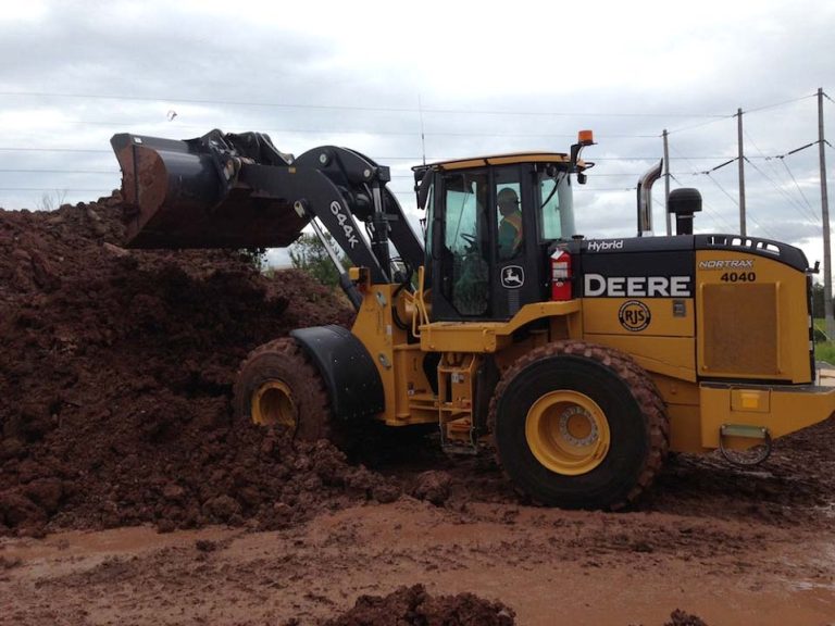 The image shows John Deere’s 644K hybrid loader operating at a construction site.