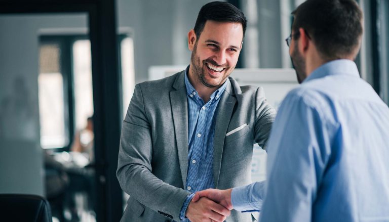 The image depicts an equipment leasing and financing broker welcoming a client with a handshake.