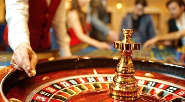 The croupier holds a roulette ball in a casino in his hand.