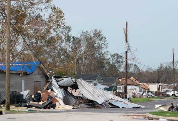 The image depicts the damage caused by a hurricane in Louisiana to a neighborhood and street.